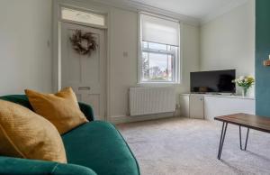 a living room with a green couch and a television at Ribby Stays - 2 bed Cottage Pet Friendly in Wrea Green
