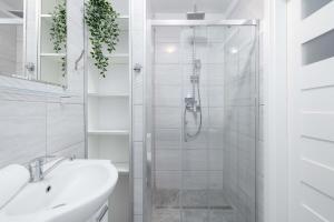ein weißes Badezimmer mit Dusche und Waschbecken in der Unterkunft Perłowa Przystań Unique Apartment with Air Conditioning and Parking Space in Kołobrzeg by Noclegi Renters in Radzikowo