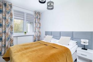 ein Schlafzimmer mit einem Bett mit einer gelben Decke in der Unterkunft Perłowa Przystań Unique Apartment with Air Conditioning and Parking Space in Kołobrzeg by Noclegi Renters in Radzikowo