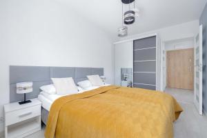 ein weißes Schlafzimmer mit einem Bett mit einer gelben Decke in der Unterkunft Perłowa Przystań Unique Apartment with Air Conditioning and Parking Space in Kołobrzeg by Noclegi Renters in Radzikowo + 12 Fotos