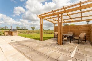 a patio with a wooden pergola and a table and chairs at Linwood in Lincoln