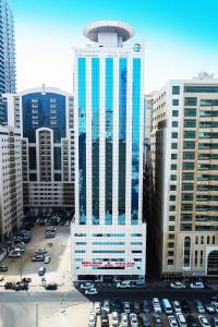 un edificio alto con coches estacionados en un estacionamiento en Royal Grand Suite Hotel, en Sharjah