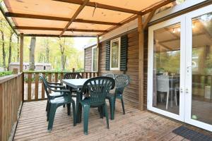 a patio with a table and chairs on a deck at La Clairière Clim Terrasse BBQ in Mirgaudon