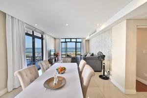 una sala da pranzo con tavolo, sedie e divano di 3 Bedroom Eden on the Bay a Big Bay