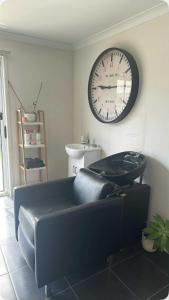a living room with a couch and a clock on the wall at Soulful healing academy in Point Cook