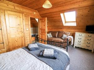 a bedroom with a bed and a couch in a cabin at Dan Y Coed in Discoed