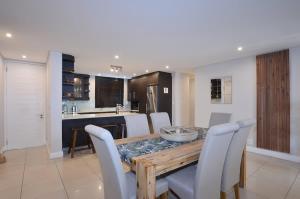 una cucina e una sala da pranzo con tavolo e sedie in legno di Elegant Contemporary Apartment at Eden on the Bay a Big Bay