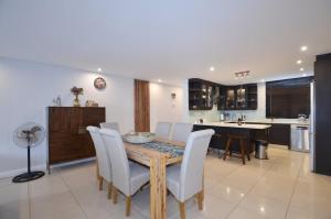 una cucina con un tavolo di legno e sedie bianche di Elegant Contemporary Apartment at Eden on the Bay a Big Bay