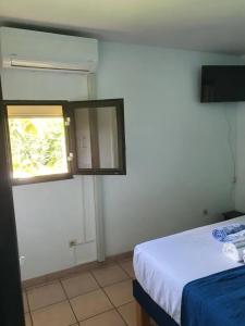 une petite chambre avec un lit et une fenêtre dans l'établissement Studio confortable vue jardin au Diamant, 25 m², à LʼAnse Caffar
