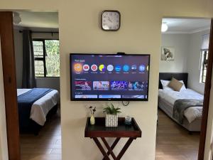 Ein Zimmer mit zwei Betten und einem Flachbildfernseher an der Wand. in der Unterkunft Khaled Estate Cottages in Hillcrest