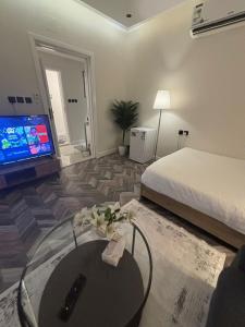 a bedroom with a bed and a table and a tv at استديو بخدمات فندقية حي الوزارات in Riyadh