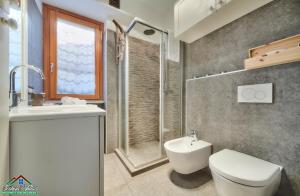 a bathroom with a toilet and a sink and a shower at Sunset Apartment with Air Conditioning and Lake View in Perledo +22 photos