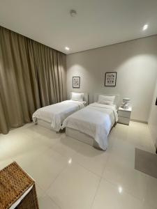 two beds in a room with white tile floors at Golden Dawn Villa in As Sīfah