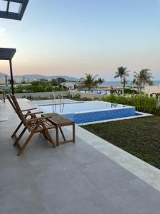 a chair and a bench next to a swimming pool at Golden Dawn Villa in As Sīfah