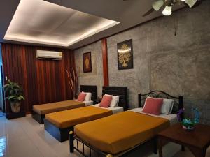 a bedroom with three beds in a room at Phakphing Erawan Homestay - พักพิง เอราวัณ โฮมสเตย์ in Tha Kradan