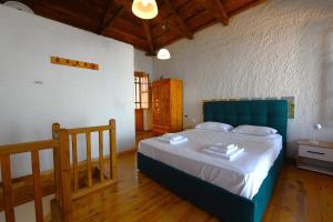 a bedroom with a bed with a blue head board at Secret Sporades Panoramic Residence in Klíma