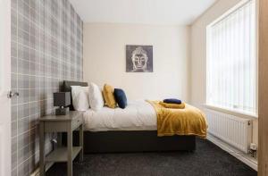 a bedroom with a bed with a yellow blanket at Oxheys Stays - Sleeps 7 - Home from Home in Preston