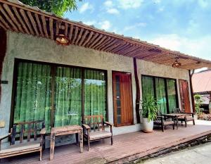 a wooden deck with chairs and a table at Phakphing Erawan Homestay - พักพิง เอราวัณ โฮมสเตย์ in Tha Kradan