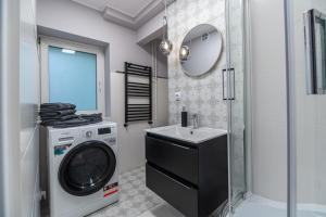 a bathroom with a washing machine and a sink at Apartly - City Home &A in Szczecin