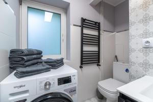 a washing machine in a bathroom with a toilet and a window at Apartly - City Home &A in Szczecin