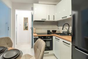a kitchen with white cabinets and a table and chairs at Apartly - City Home &A in Szczecin