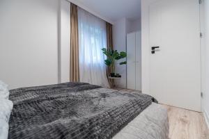 a white bedroom with a bed and a window at Apartly - City Home &A in Szczecin