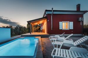 a swimming pool with white chairs and a house at Casa Lutoma in Kmeti