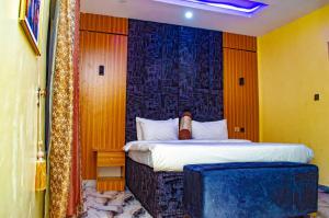 a bedroom with a bed with a blue wall at Bremmy Multilinks Hotels and Suites in Asaba +7 photos