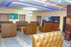 a waiting room with brown leather chairs and a bar at Bremmy Multilinks Hotels and Suites in Asaba