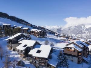 une station de ski avec des bâtiments enneigés sur une montagne dans l'établissement Charmant T2 avec terrasse, proche pistes, parking gratuit - FR-1-755-21, à Aime La Plagne