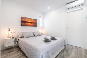 a white bedroom with a bed with two towels on it at Duplex-Port-Valencia in Valencia