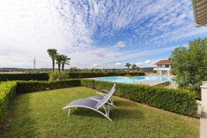 a white chair sitting on the grass near a swimming pool at Vivere il Parco in Lonato