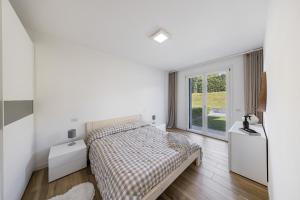 a white bedroom with a bed and a window at Vivere il Parco in Lonato