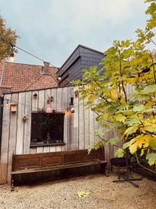 布鲁日Tiny House The Bird House的一座木制建筑，前面有一张长凳