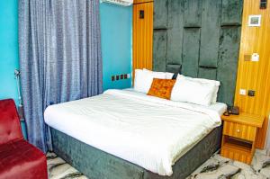 a bedroom with a bed and a red chair at Bremmy Multilinks Hotels and Suites in Asaba