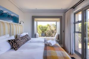 ein Schlafzimmer mit einem Bett und einem großen Fenster in der Unterkunft Dune Seaside Cottage in Plettenberg Bay + 27 Fotos