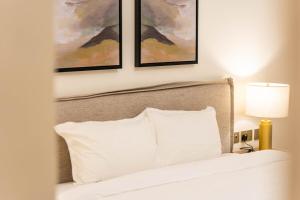 ein Schlafzimmer mit einem Bett mit weißen Kissen und Gemälden in der Unterkunft Yas Golf Collection 1 BR Near Theme Parks in Abu Dhabi