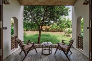 a patio with two chairs and a table and a tree at Le Casa Lion Resort A Premium Resort In Sasan Gir in Sasan Gir