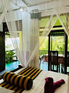 une chambre avec un lit avec des rideaux et un balcon dans l'établissement " YOLO " LOVELY COTTAGE, à Ella
