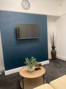 ein Wohnzimmer mit einer blauen Wand, an dem ein Tisch und eine Uhr stehen. in der Unterkunft A&A Luxury Stay Tunstall in Sunderland