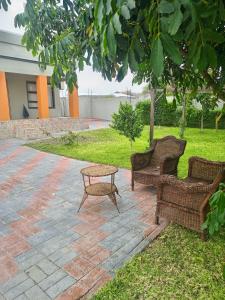 Dos sillas de mimbre y una mesa en un patio de ladrillo en AYA Apartment, en Maun