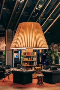 a large lamp in a room with couches and books at Pentahotel Leipzig in Leipzig