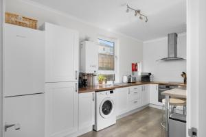 a kitchen with white cabinets and a washer and dryer at Sidlaw View in Dundee