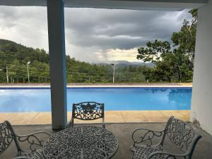een patio met 2 stoelen en een tafel naast een zwembad bij The Green Garniya Poolside and Mountain View Hotel in Belihul Oya