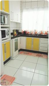 een keuken met gele en witte kasten en apparaten bij Cantinho da paz in Paranavaí