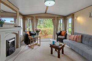 a living room with a couch and a fireplace at Greendale Splash Escape - No Commercial Sign written Vehicles,Fishing Nearby & Communal Swimming Pool Open April to September in Tedburn Saint Mary