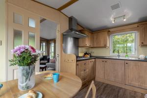 a kitchen with a table and a vase of flowers at Greendale Splash Escape - No Commercial Sign written Vehicles,Fishing Nearby & Communal Swimming Pool Open April to September in Tedburn Saint Mary
