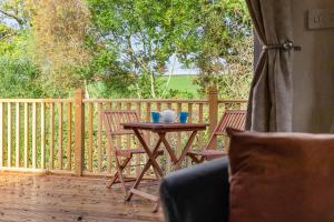 a wooden deck with a table and chairs on a porch at Greendale Splash Escape - No Commercial Sign written Vehicles,Fishing Nearby & Communal Swimming Pool Open April to September in Tedburn Saint Mary +37 photos
