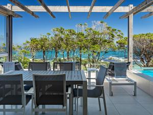 a table and chairs on a patio with a view of the ocean at Blue Views Penthouse Beachfront Apartment with Pool in Cape Town