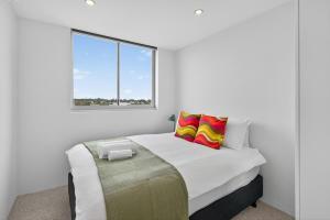 クロヌラにあるThe Oceanfront Sanctuary Spa & Parkingの白いベッドルーム(カラフルな枕2つ付きのベッド1台付)